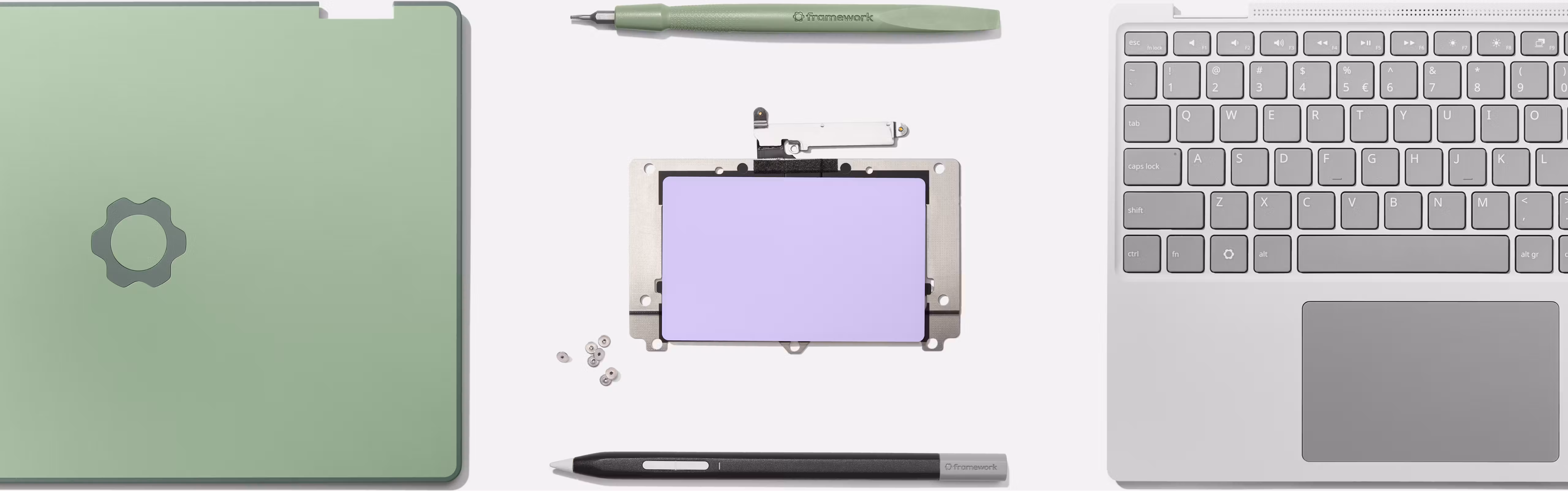Disassembled parts of a Framework Laptop 12 laid out, including the top cover, a green stylus, a trackpad module with lavender surface, small screws, a black stylus, and an input cover.