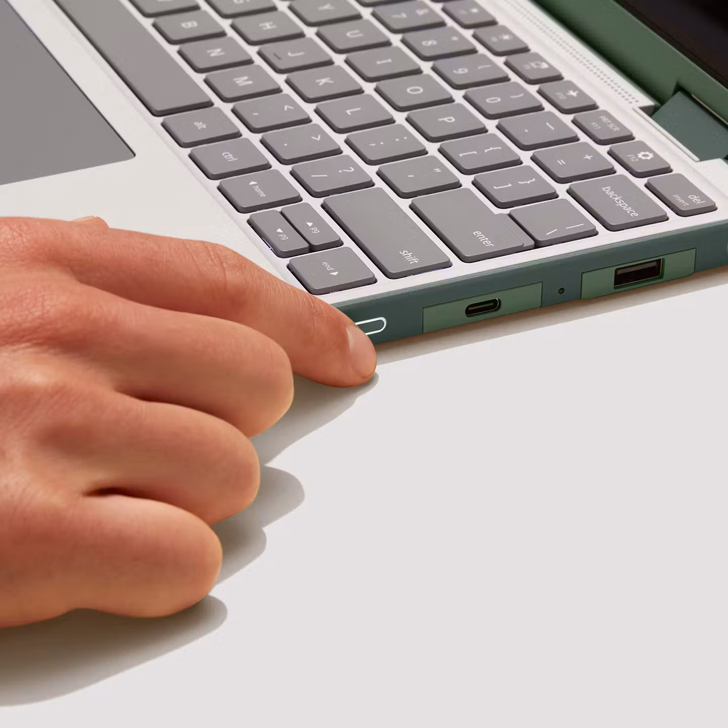 Close-up of a finger pressing the fingerprint sensor on the side of a Sage Framework Laptop 12.