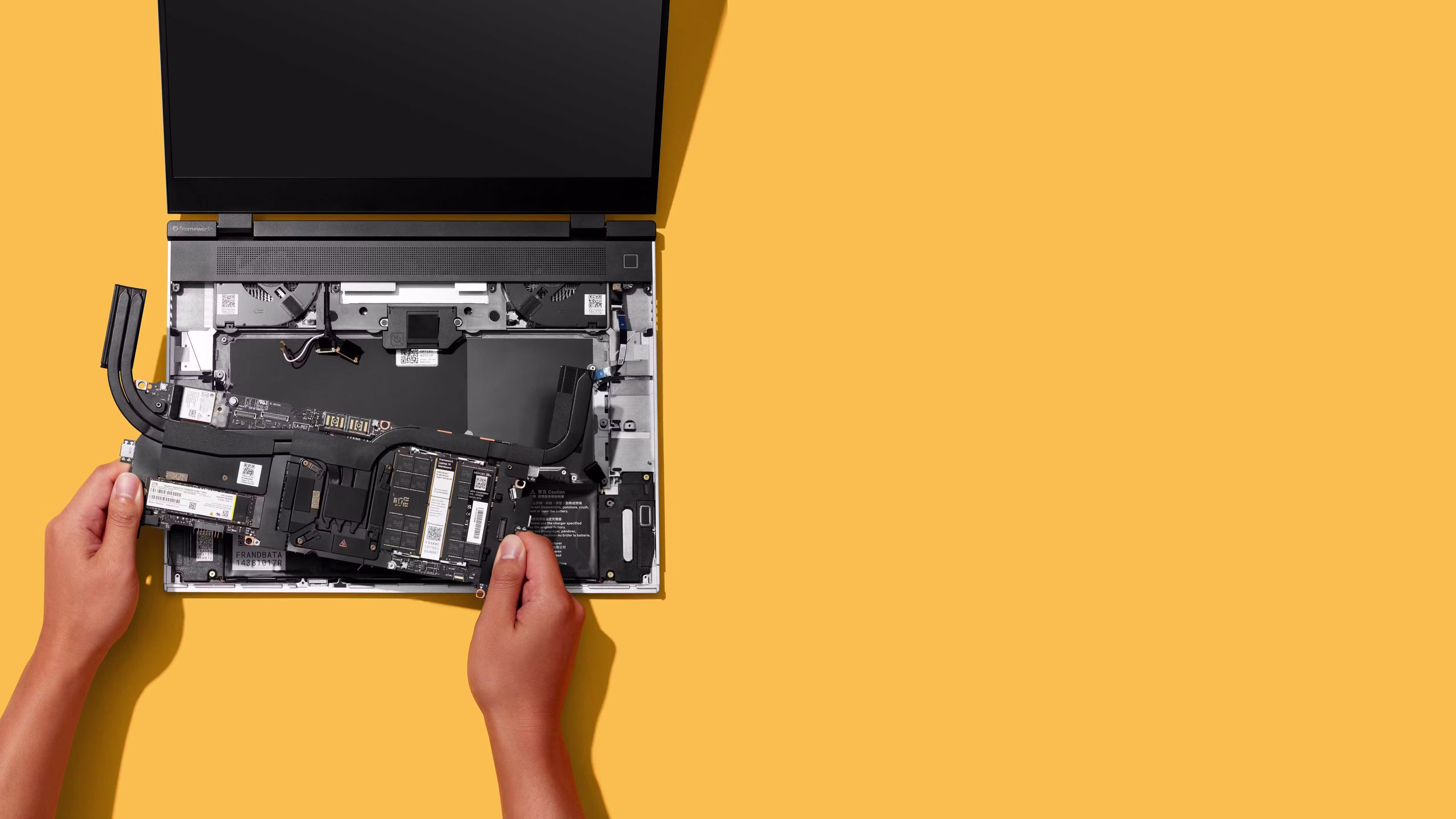 Top-down studio shot of a Framework Laptop 16 with a person installing the mainboard.