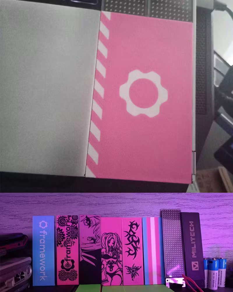 Close-up shot of custom 3D printed pink spacers for Framework Laptop 16, accompanied by a large stack of different kinds of 3D printed spacers.
