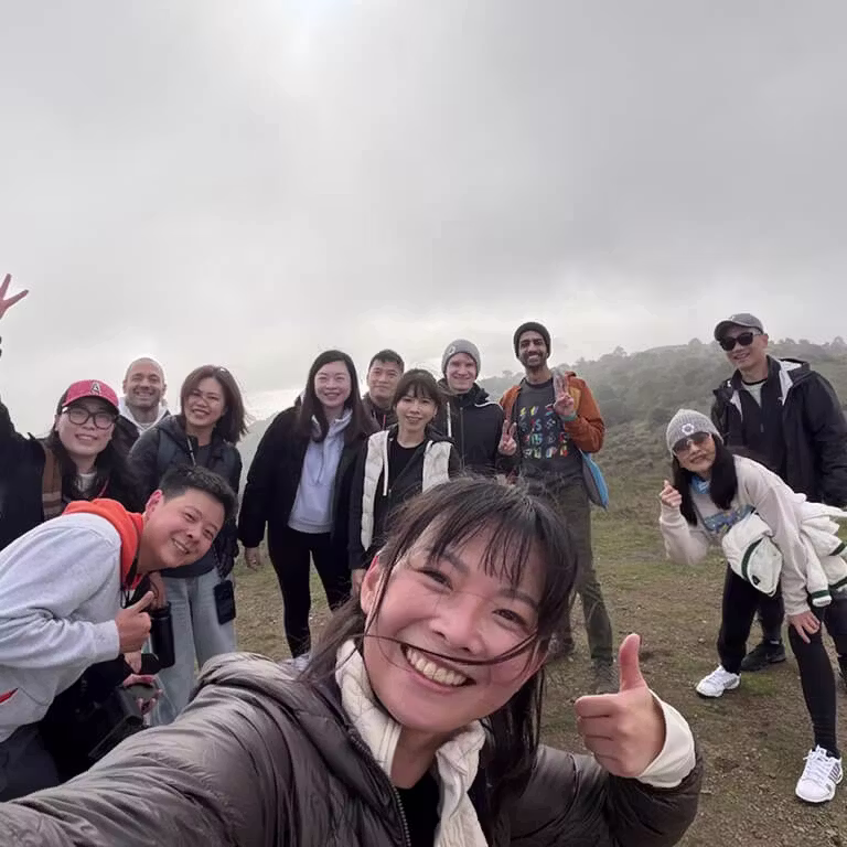 A cheerful group of Framework employees taking a selfie together on a foggy hilltop during an outdoor team hike.
