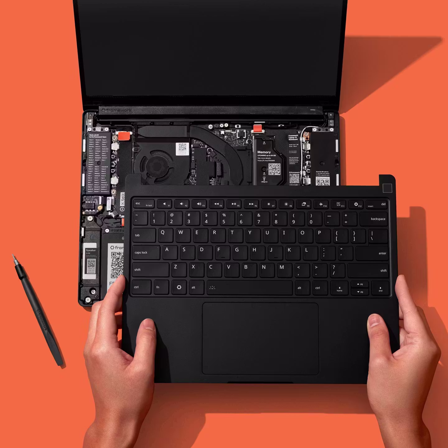 A top-down installation studio shot of a Framework Laptop 13 Pro against a Framework orange backdrop.