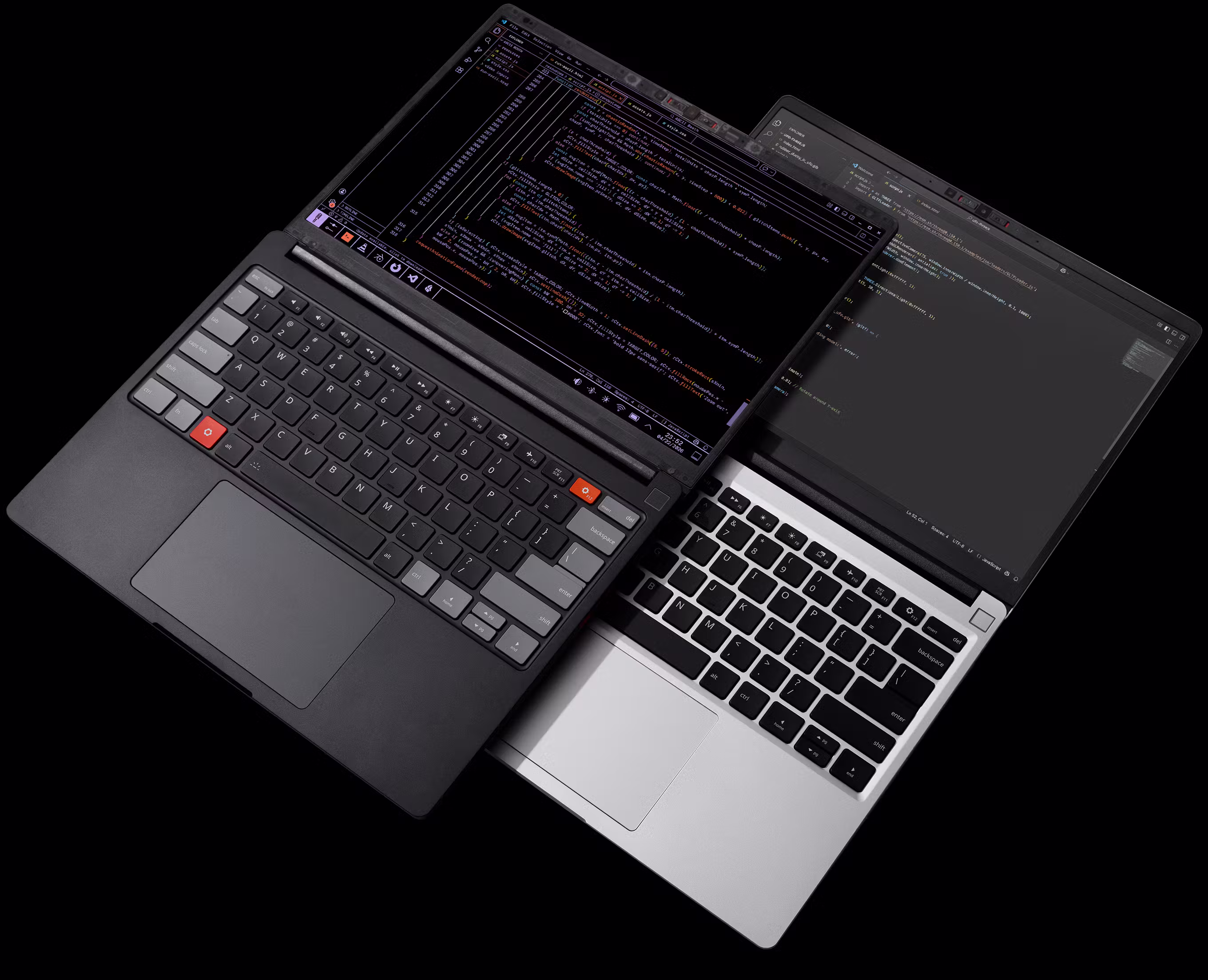 A top-down, high-contrast photograph against a black background featuring two Framework Laptops overlapping diagonally. One laptop is Framework Laptop 13 Pro Graphite, and the other is the Framerwork Laptop 13 Silver.