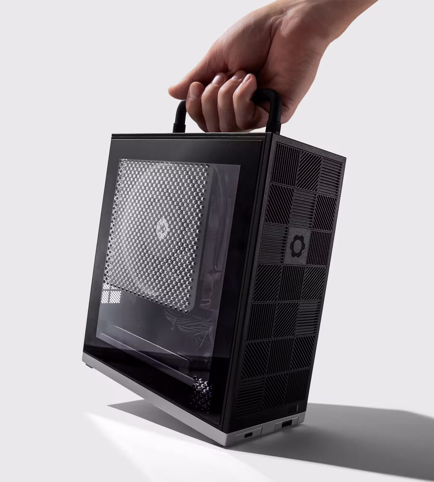 A hand lifts the assembled Framework Desktop by its top handle.